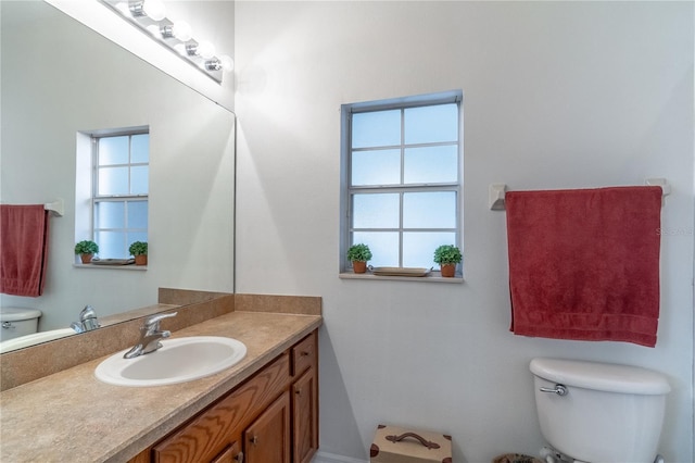 bathroom featuring a healthy amount of sunlight, vanity, and toilet