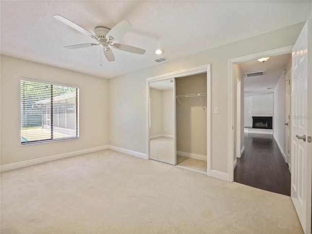 unfurnished bedroom featuring ceiling fan, light colored carpet, and a closet