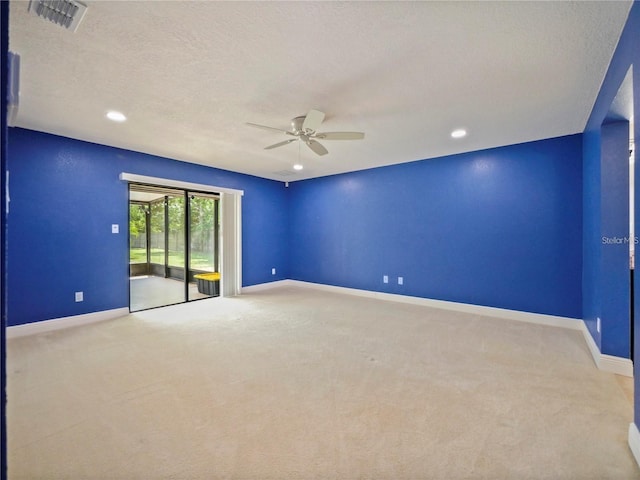 spare room featuring light carpet, ceiling fan, and a textured ceiling