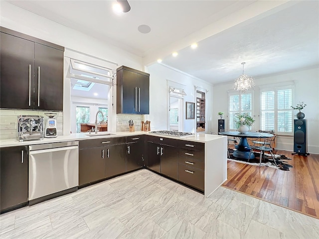 kitchen with sink, decorative backsplash, hanging light fixtures, stainless steel appliances, and a healthy amount of sunlight