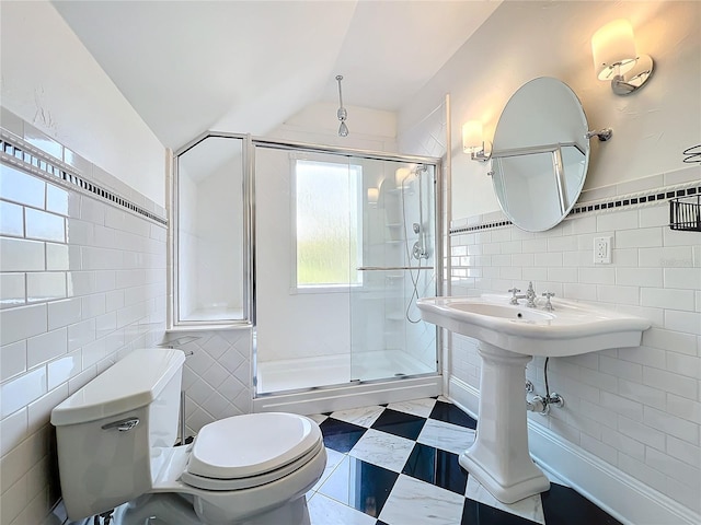 bathroom featuring tile walls, vaulted ceiling, a shower with door, and toilet