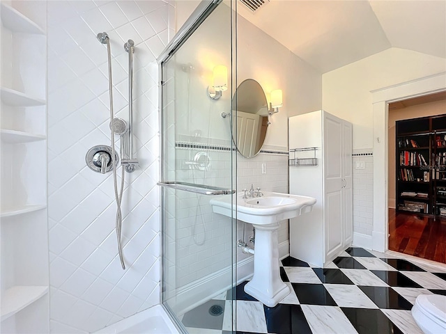 bathroom featuring tile walls, lofted ceiling, and walk in shower