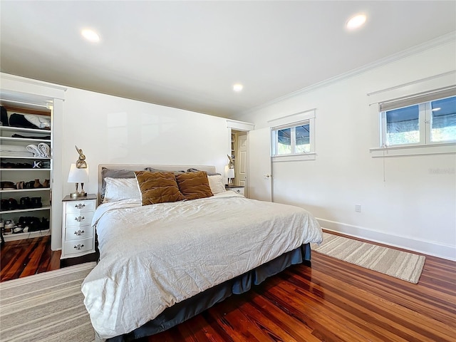 bedroom with dark wood-type flooring, ornamental molding, and a spacious closet