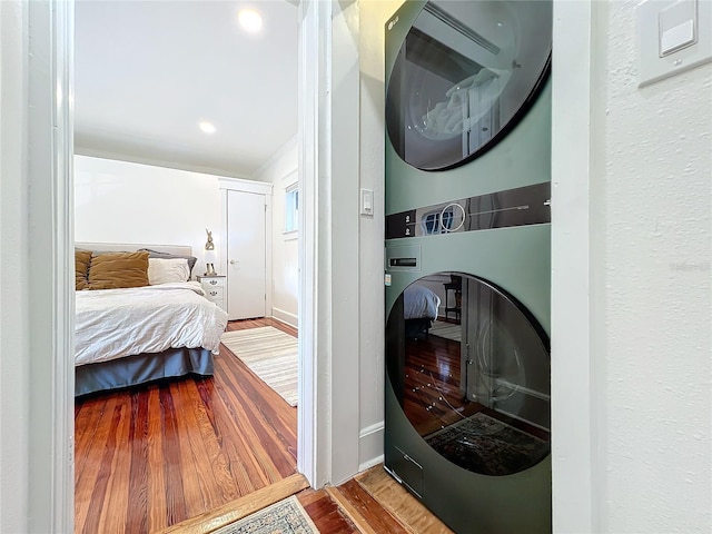 washroom with stacked washer / drying machine and wood-type flooring