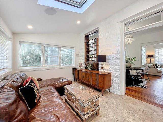 living room featuring vaulted ceiling with skylight and light wood-type flooring