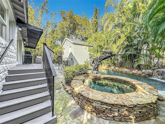 view of swimming pool featuring an in ground hot tub, a grill, and a deck