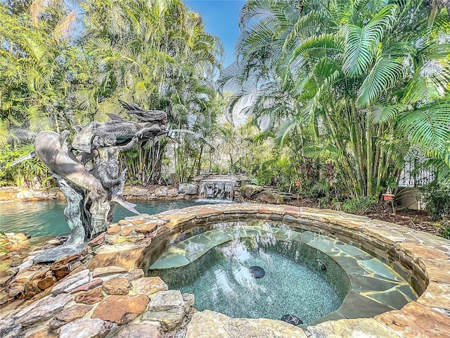 view of pool featuring a small pond and an in ground hot tub