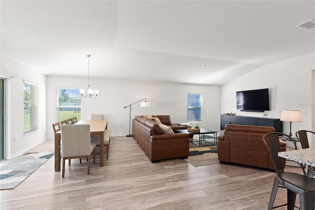 living room featuring a textured ceiling, vaulted ceiling, a chandelier, and light wood-type flooring