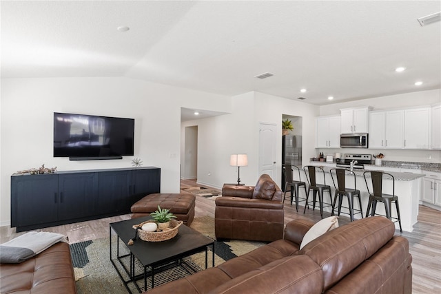 living room with vaulted ceiling and light hardwood / wood-style floors