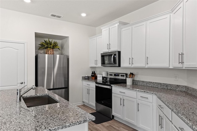 kitchen with white cabinetry, sink, stainless steel appliances, and light stone countertops