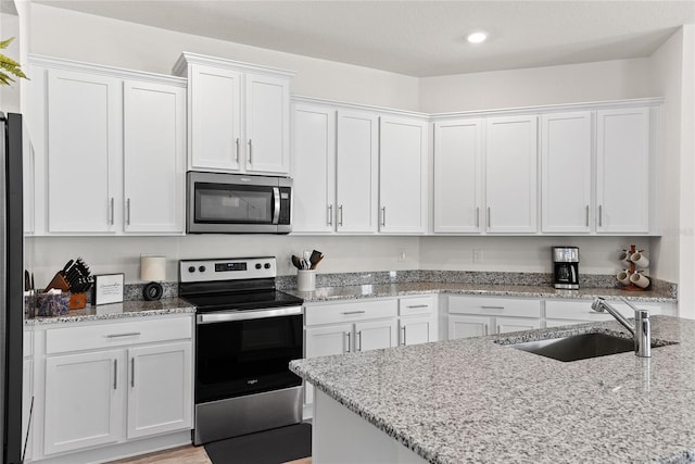 kitchen featuring white cabinetry, sink, light stone counters, and stainless steel appliances