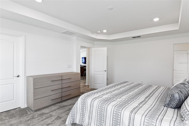 bedroom featuring a raised ceiling and carpet