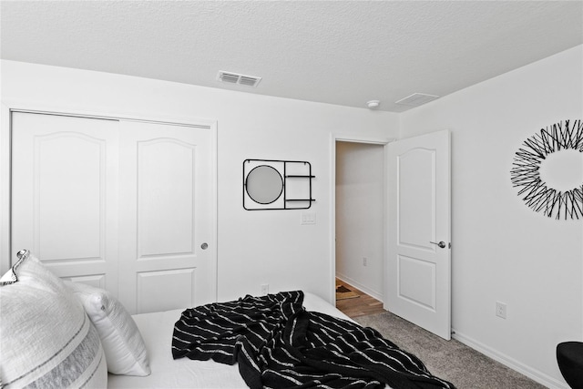 bedroom featuring a closet, a textured ceiling, and carpet flooring