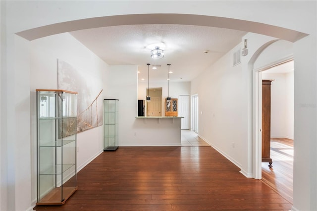 unfurnished living room featuring dark wood-type flooring and a textured ceiling