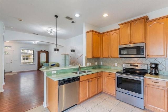 kitchen featuring pendant lighting, sink, decorative backsplash, light hardwood / wood-style floors, and stainless steel appliances