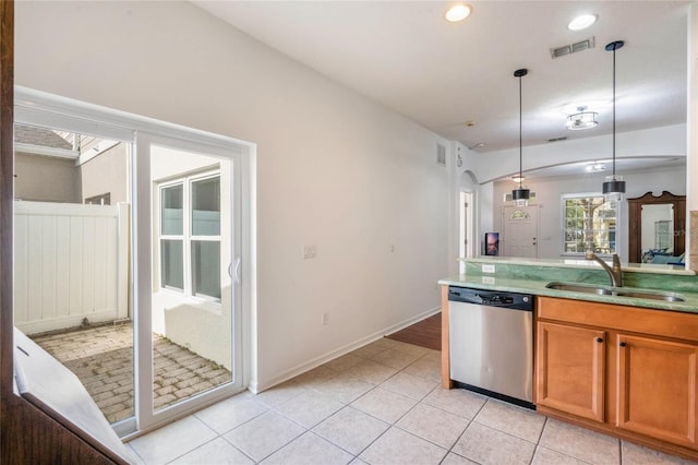 kitchen featuring sink, light tile patterned floors, stainless steel dishwasher, and hanging light fixtures