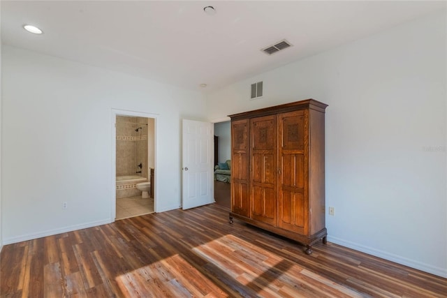 unfurnished bedroom featuring dark wood-type flooring and connected bathroom