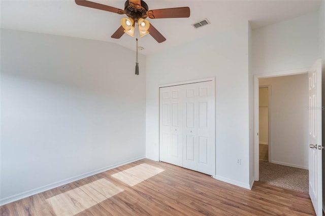 unfurnished bedroom with ceiling fan, lofted ceiling, light hardwood / wood-style floors, and a closet