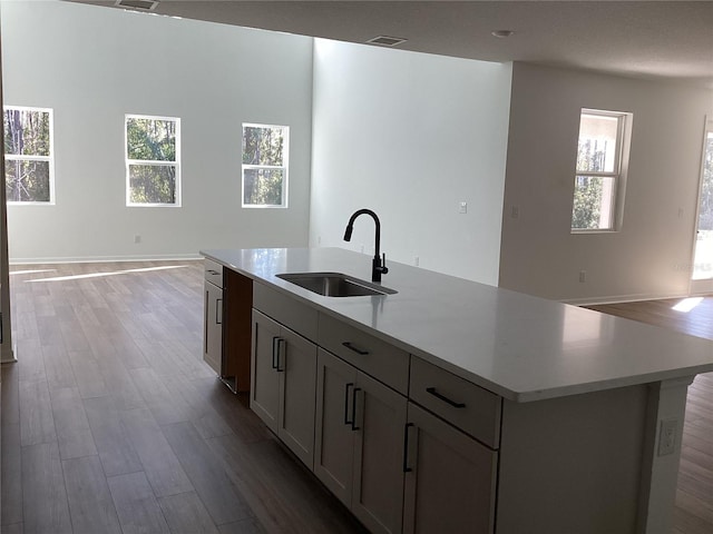 kitchen featuring light countertops, visible vents, open floor plan, a sink, and wood finished floors