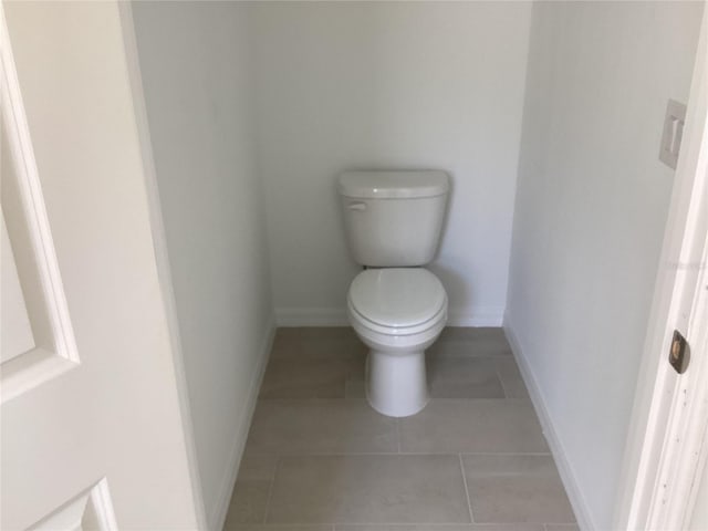 bathroom with toilet, tile patterned flooring, and baseboards