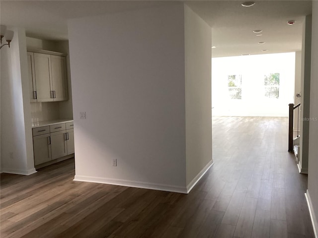 hall with dark wood-style flooring and baseboards