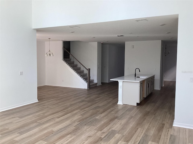 kitchen featuring light countertops, light wood-style flooring, open floor plan, a sink, and an island with sink