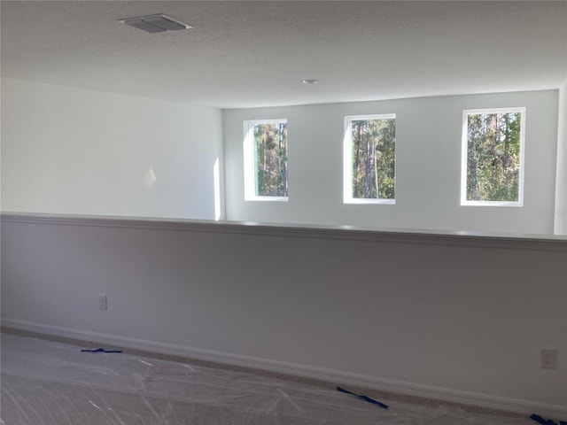 spare room with visible vents, a textured ceiling, and baseboards