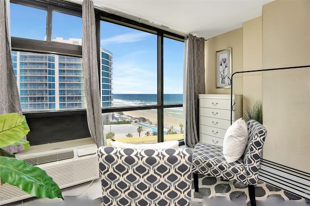 bedroom featuring cooling unit, expansive windows, a beach view, and a water view