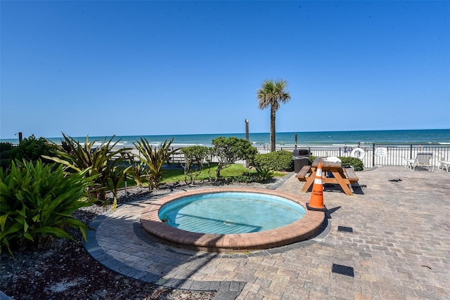 view of swimming pool with a water view and a view of the beach