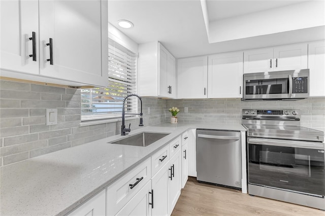 kitchen with white cabinetry, sink, light stone counters, and stainless steel appliances