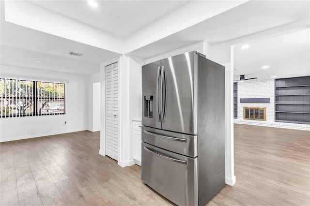 kitchen featuring built in shelves, white cabinetry, stainless steel fridge with ice dispenser, light hardwood / wood-style flooring, and a fireplace