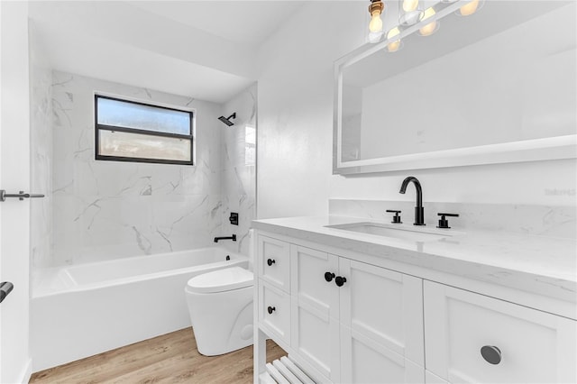 full bathroom with vanity, tiled shower / bath, wood-type flooring, and toilet