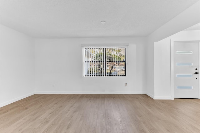 unfurnished room with a textured ceiling and light hardwood / wood-style floors