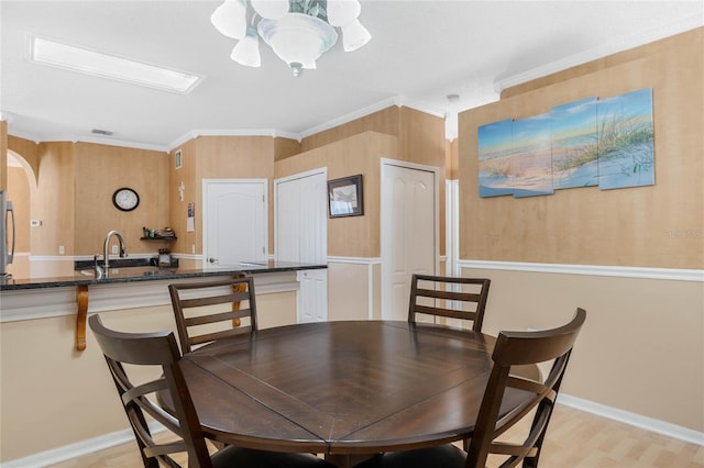 dining area with ornamental molding, sink, and light wood-type flooring