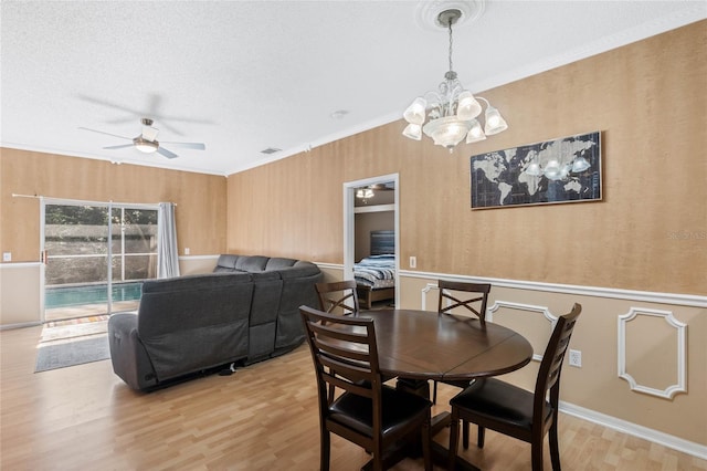 dining area featuring crown molding, ceiling fan with notable chandelier, and light wood-type flooring