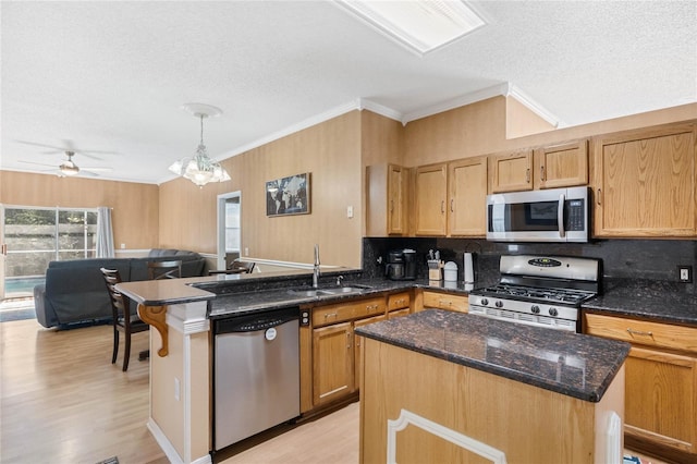 kitchen with decorative light fixtures, dark stone countertops, appliances with stainless steel finishes, a kitchen island, and a wealth of natural light