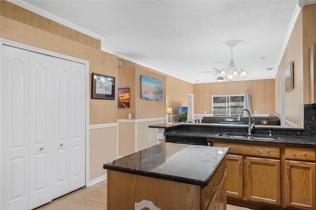 kitchen featuring a center island, sink, hanging light fixtures, and dark stone countertops