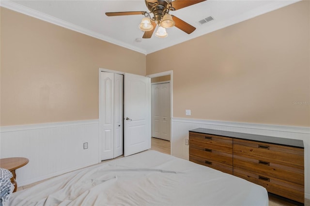 bedroom featuring ceiling fan, ornamental molding, and a closet