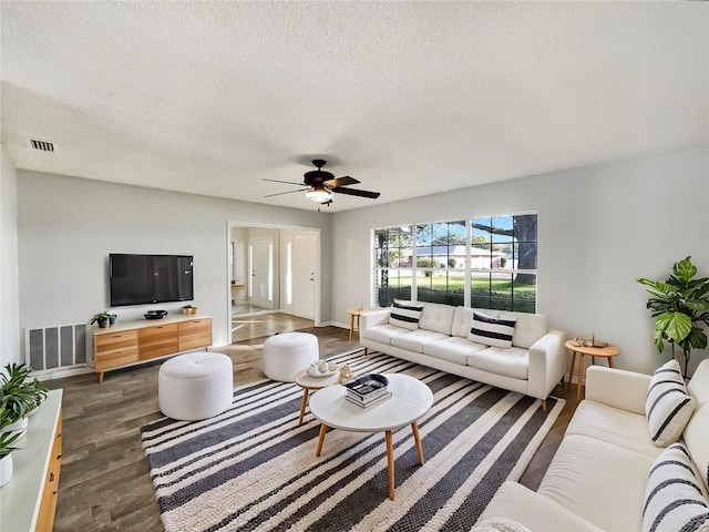 living room with ceiling fan, dark hardwood / wood-style floors, and a textured ceiling