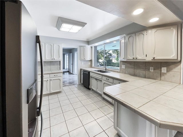 kitchen with stainless steel refrigerator with ice dispenser, sink, white cabinetry, tile countertops, and dishwasher