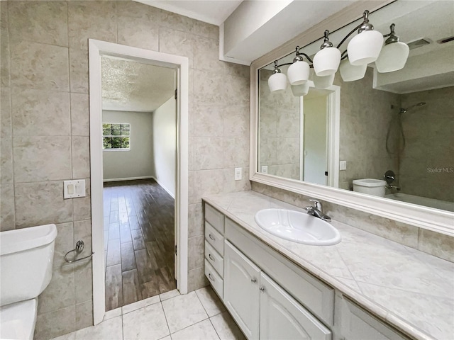 bathroom featuring tile walls, vanity, tile patterned flooring, and toilet