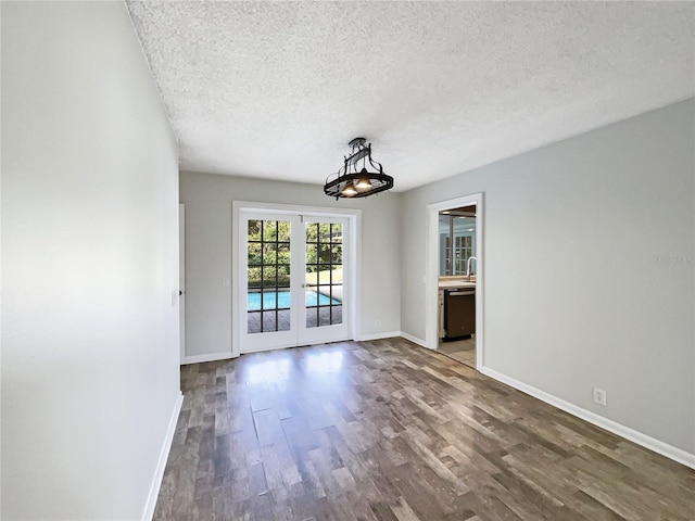 empty room with sink, a textured ceiling, dark hardwood / wood-style flooring, and french doors