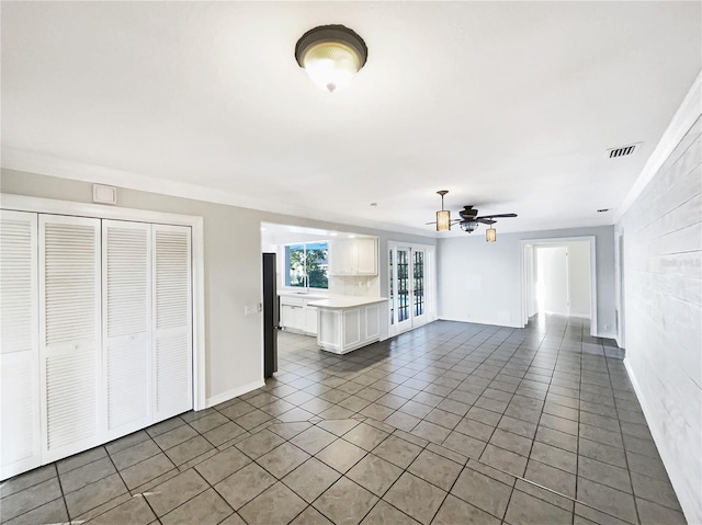 unfurnished living room featuring sink, tile patterned floors, ceiling fan, and french doors