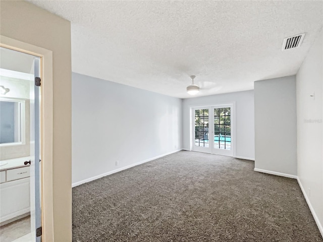 unfurnished room with french doors, carpet, and a textured ceiling