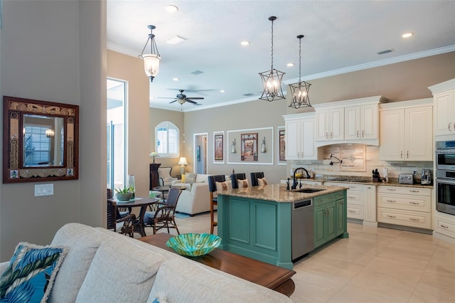 kitchen featuring sink, appliances with stainless steel finishes, hanging light fixtures, green cabinetry, and a center island with sink