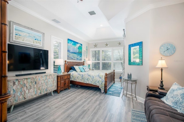 bedroom featuring crown molding, light hardwood / wood-style floors, and a tray ceiling