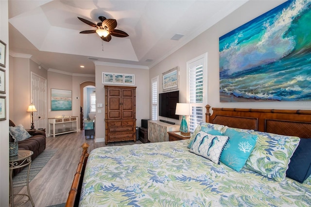 bedroom featuring a raised ceiling, ornamental molding, hardwood / wood-style flooring, and ceiling fan