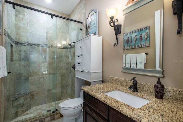 bathroom with a shower with door, vanity, and toilet