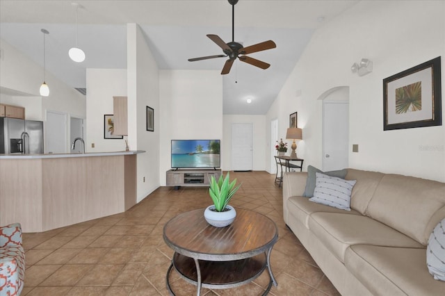 living room featuring light tile patterned flooring, high vaulted ceiling, sink, and ceiling fan