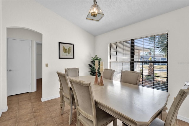 tiled dining area with lofted ceiling and a textured ceiling